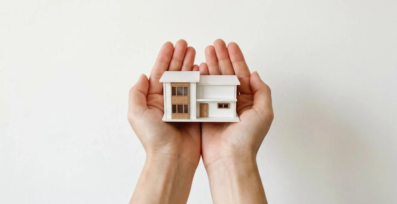 Mains soutenant une maquette de maison symbolisant l'aide à l'accession à la propriété